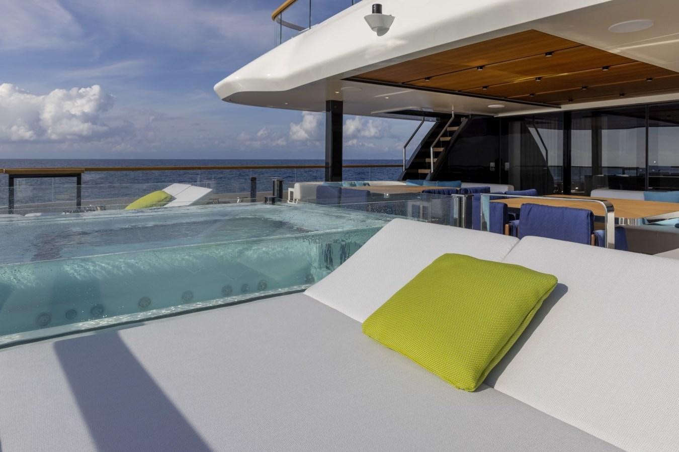 a swimming pool with a deck and chairs and a building in the background aboard C Yacht for Sale