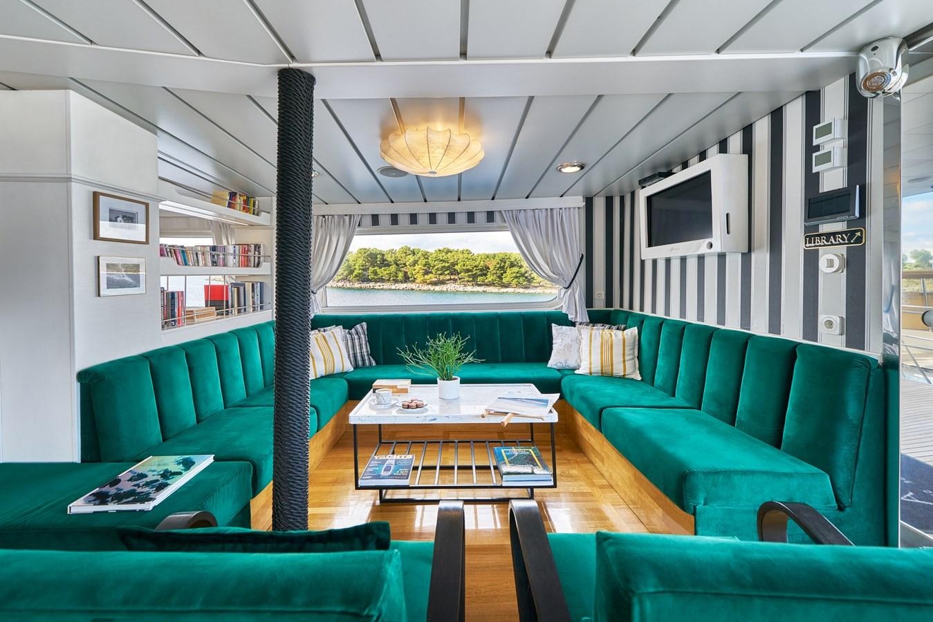 a living room with green couches aboard LA PERLA Yacht for Charter