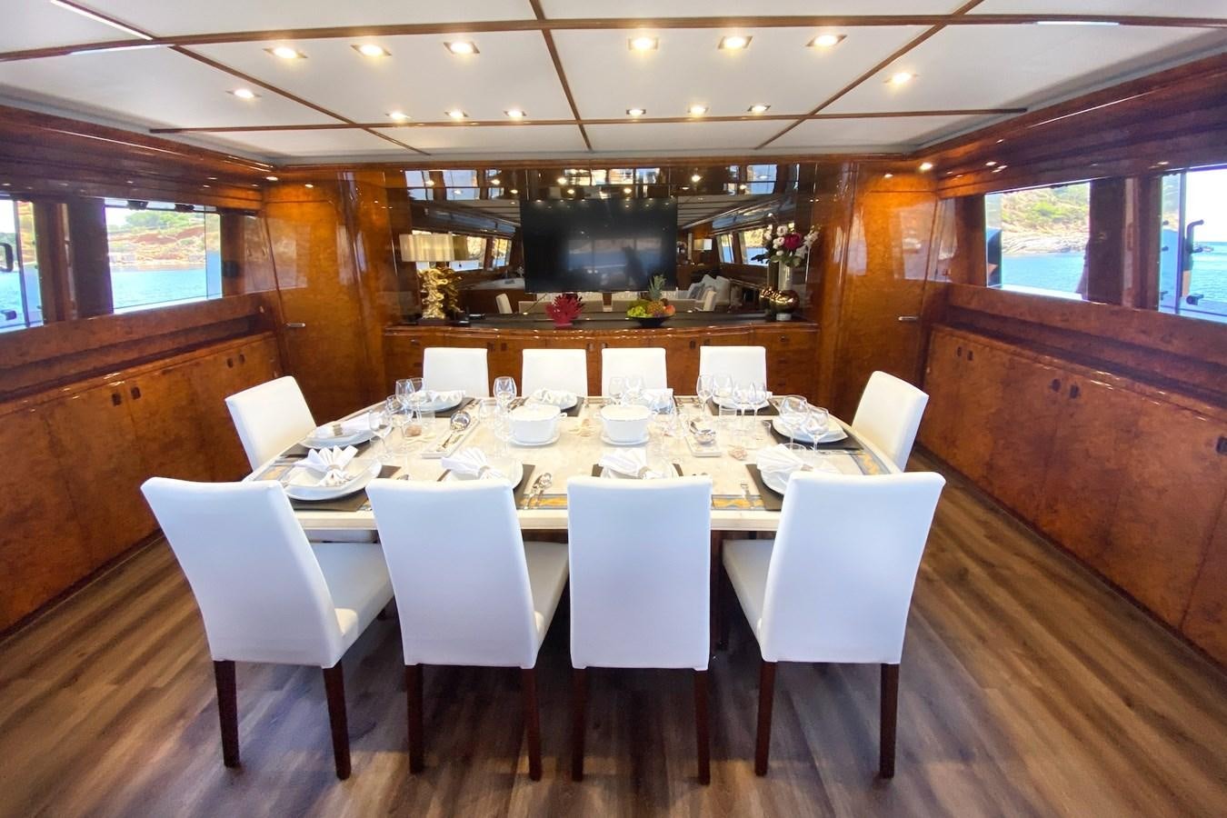 a large dining table with white chairs aboard PAULA III Yacht for Sale