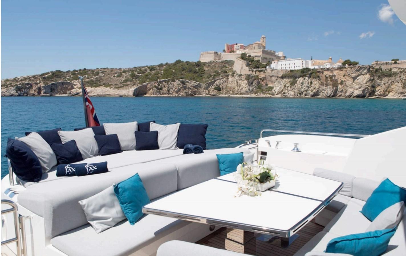 a white lounge chair with a white table and white table on a beach with a red and blue aboard JAX OF IBIZA Yacht for Sale