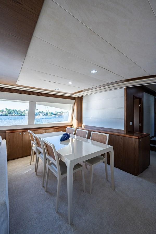 a white table and chairs in a room with a window and a view of water aboard FERRETTI Yacht for Sale