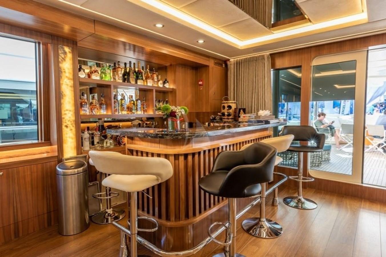 a room with a bar and chairs aboard ARESTEAS Yacht for Sale