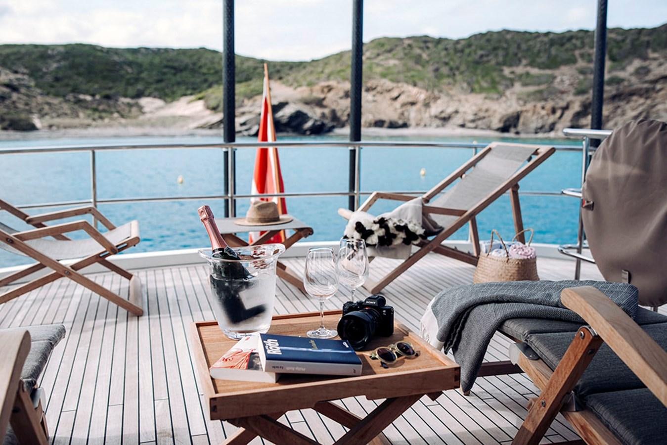 a table with a glass and a camera on it aboard LAS NINAS Yacht for Sale