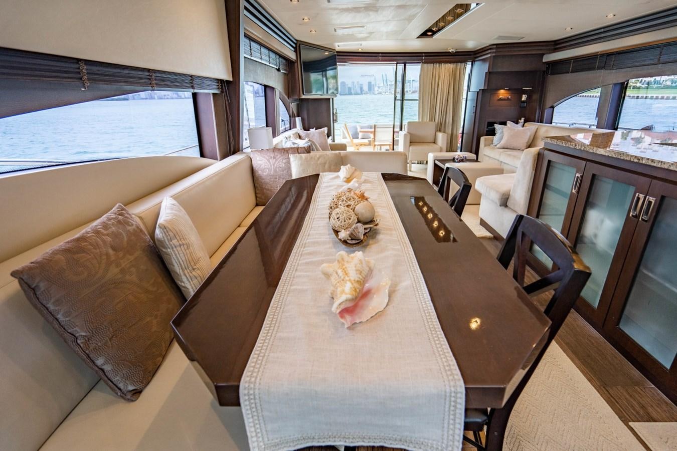 a dining table and chairs in a room with a large window aboard MAYA Yacht for Sale