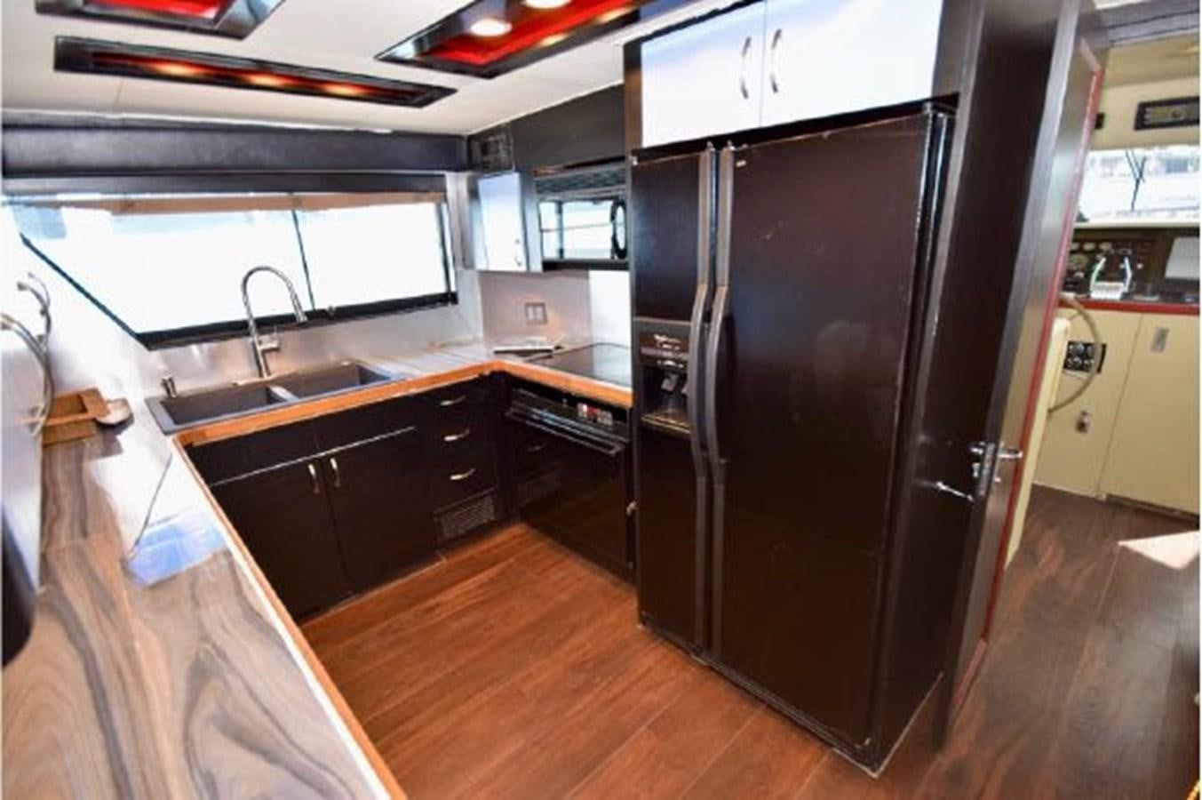 a kitchen with a black refrigerator aboard MAC LL Yacht for Sale