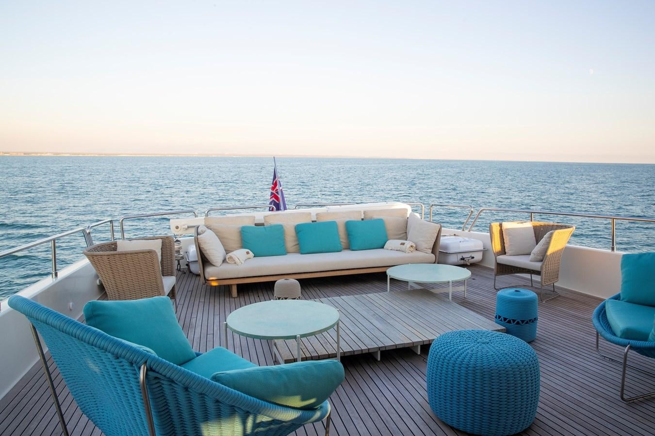 a deck with chairs and tables on it by the water aboard BIM Yacht for Sale