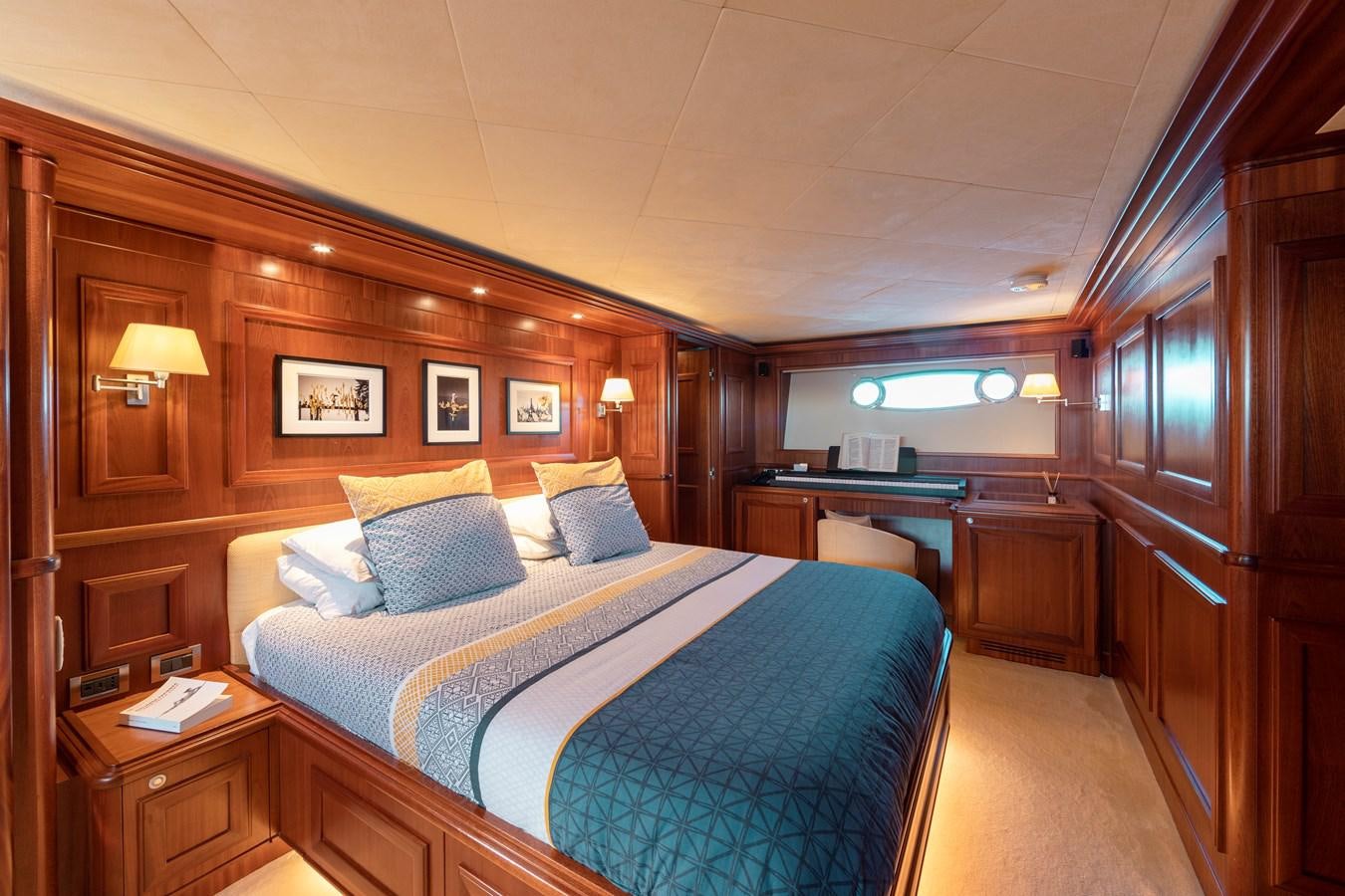 a bedroom with a bed and desk aboard BIM Yacht for Sale