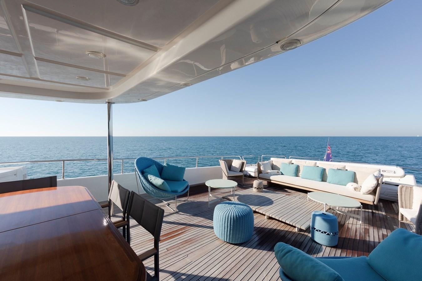 a lounge area with chairs and tables on a deck overlooking the ocean aboard BIM Yacht for Sale