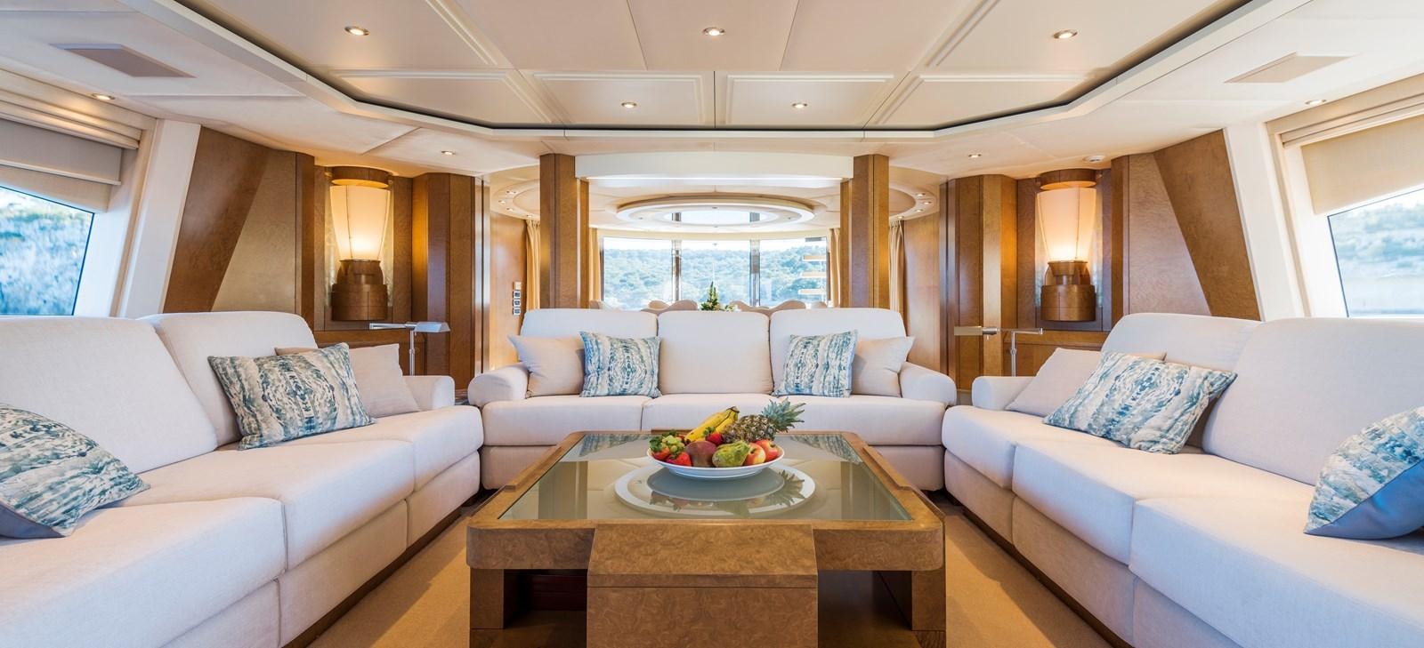 a living room with a white couch and a table with a bowl of fruit on it aboard BENITA BLUE Yacht for Charter