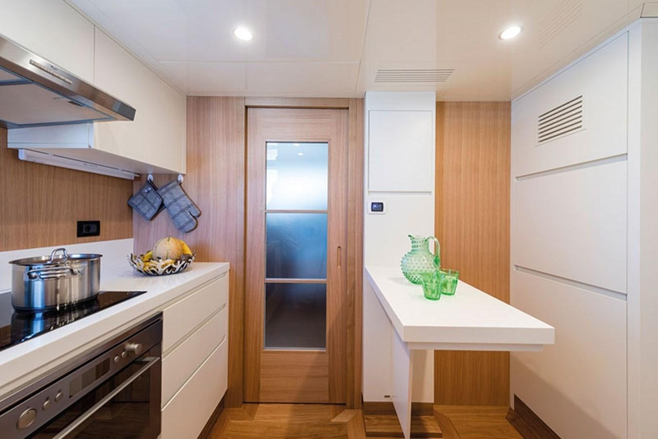 a kitchen with a table and a refrigerator aboard UNICA Yacht for Sale
