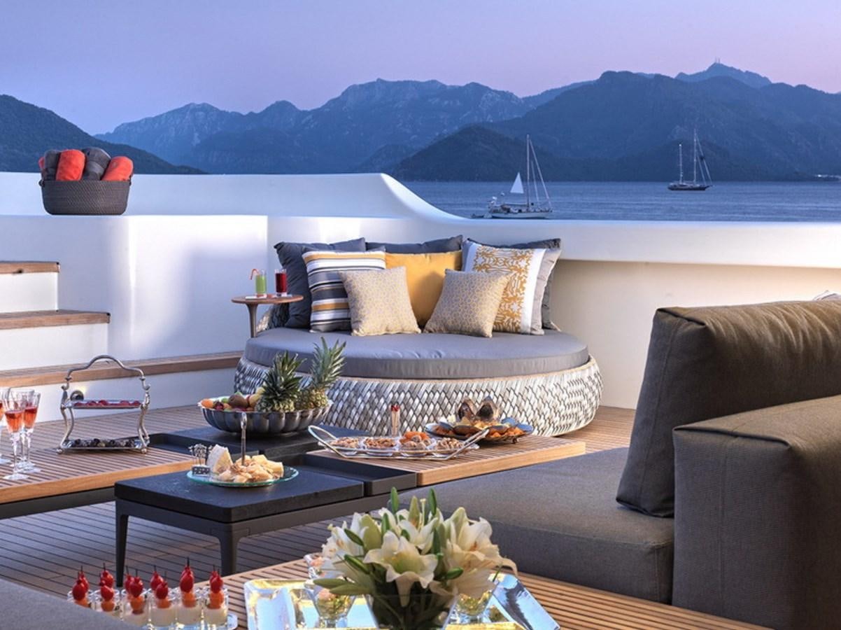 a living room with a large body of water and a large boat in the background aboard QUEEN MARE Yacht for Charter