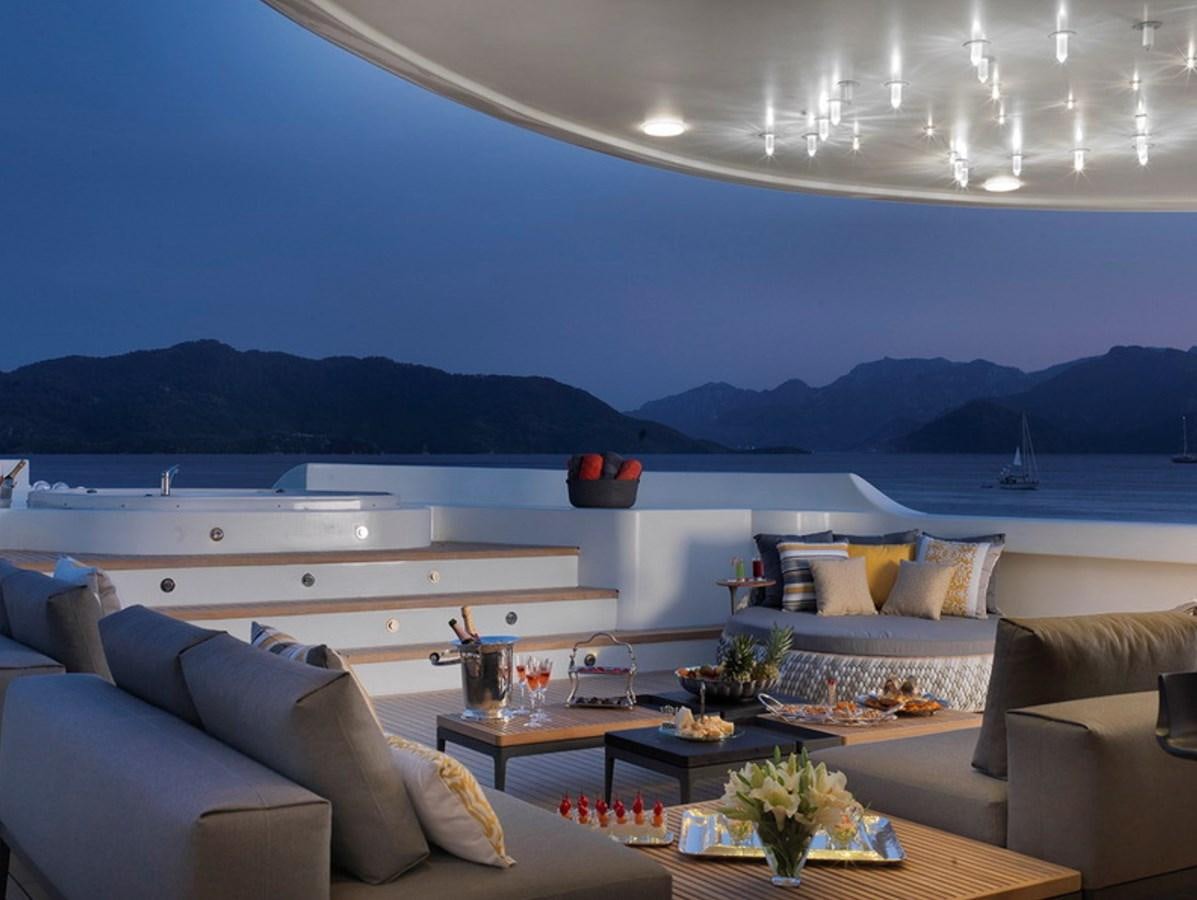 a living room with a large body of water and mountains in the background aboard QUEEN MARE Yacht for Sale