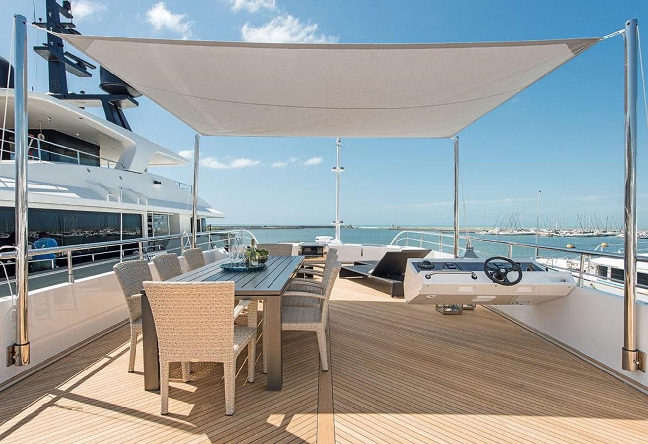 a deck with a table and chairs on it aboard FAST & FURIOUS Yacht for Sale