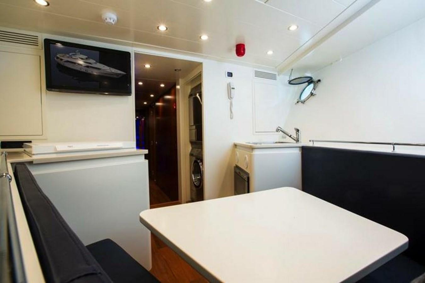 a kitchen with a table and a tv on the wall aboard M.C Yacht for Sale