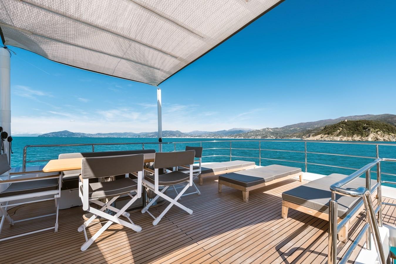 a deck with chairs and tables on it by the water aboard ARCHIPELAGO Yacht for Sale