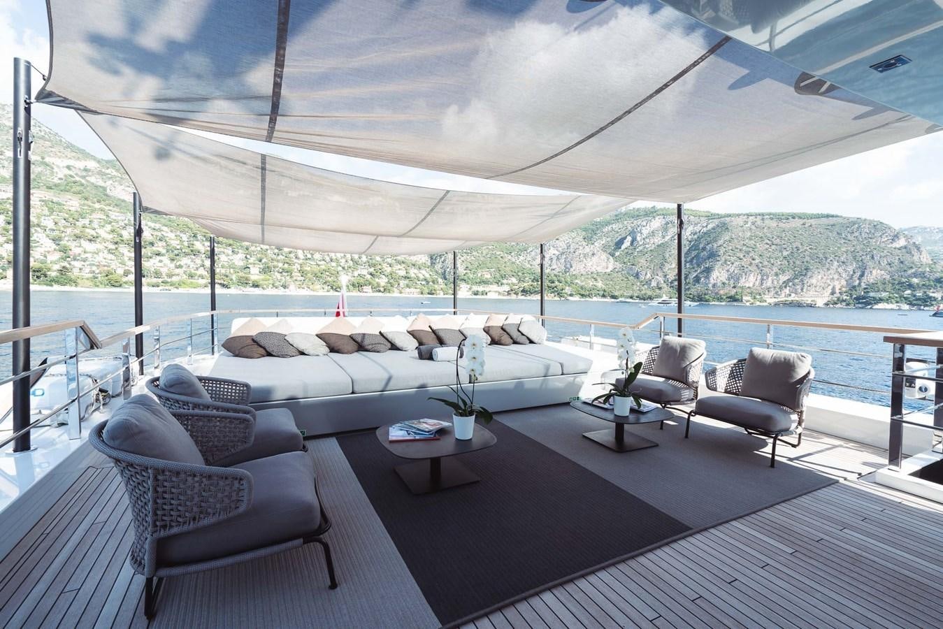 a large white lounge chair on a deck overlooking a large body of water aboard JESMA II Yacht for Sale