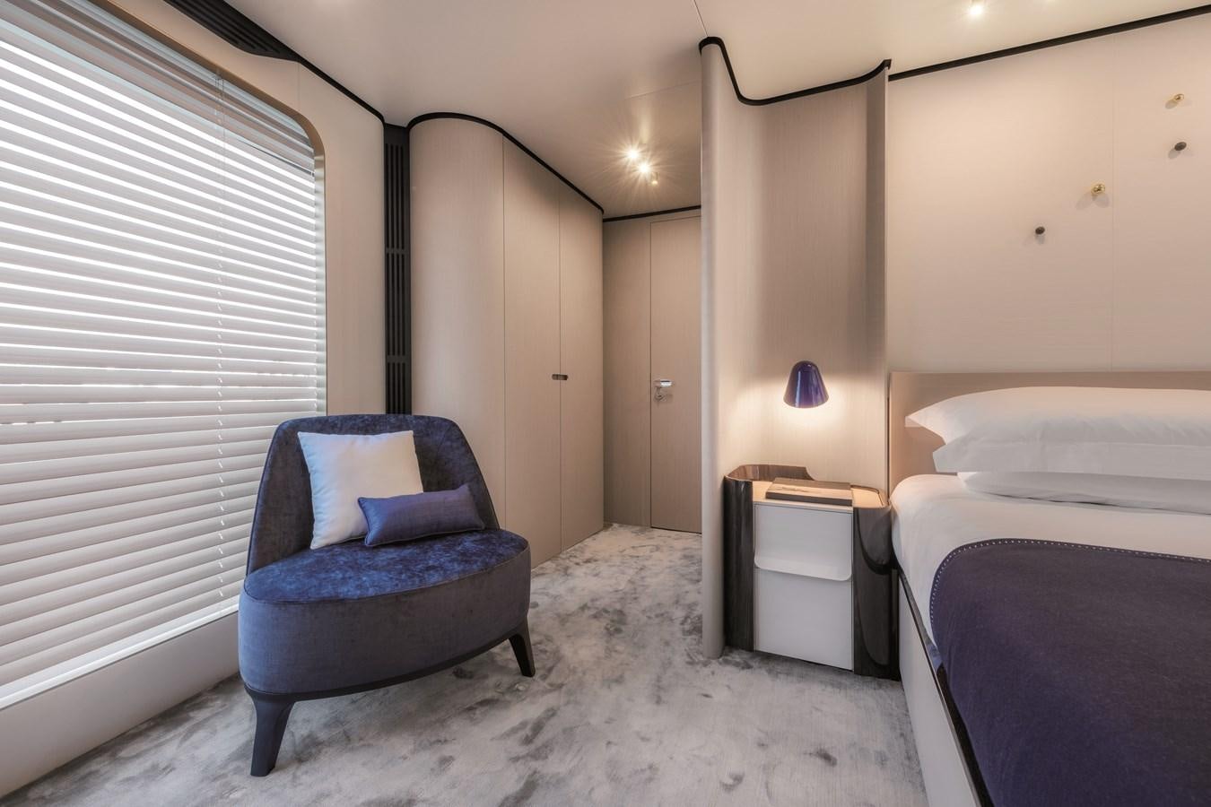 a bedroom with a blue chair aboard LA MAMA Yacht for Sale