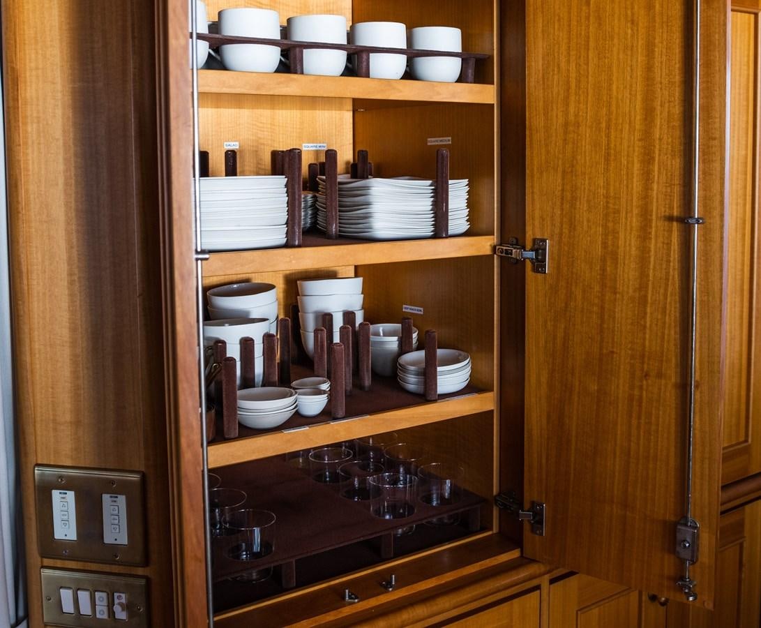 a wooden cabinet with a shelf of dishes aboard FORTUNA Yacht for Sale