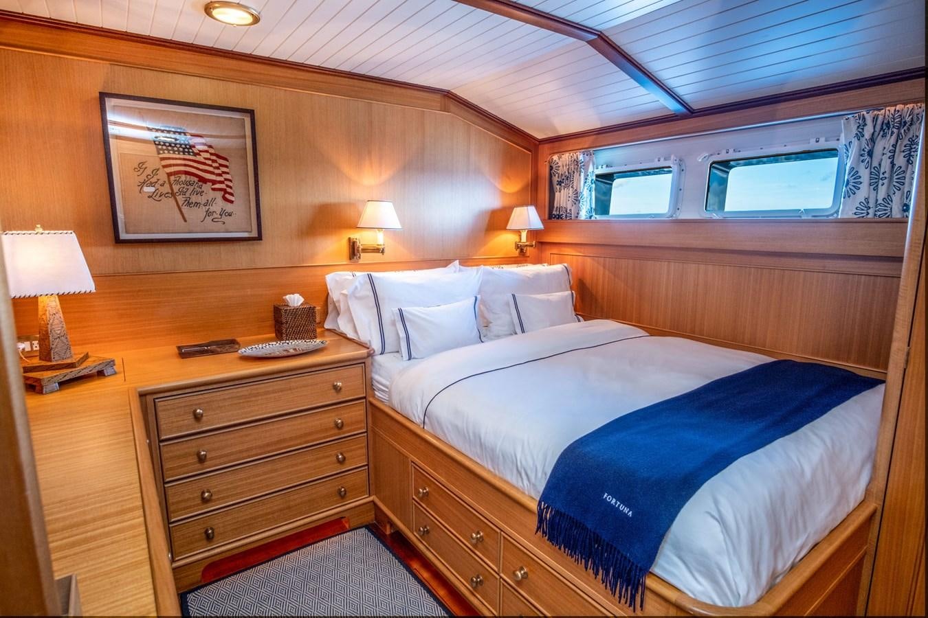 a hotel room with a bed and a dresser aboard FORTUNA Yacht for Sale