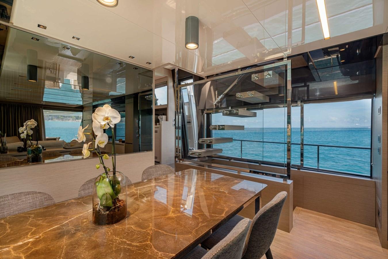 a table with flowers in a room with a large window aboard LUCKY Yacht for Sale