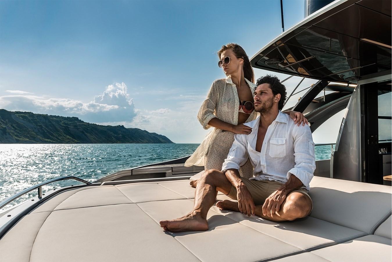 a man and woman sitting on a boat with a woman holding a bottle aboard PERSHING 8X   Yacht for Sale