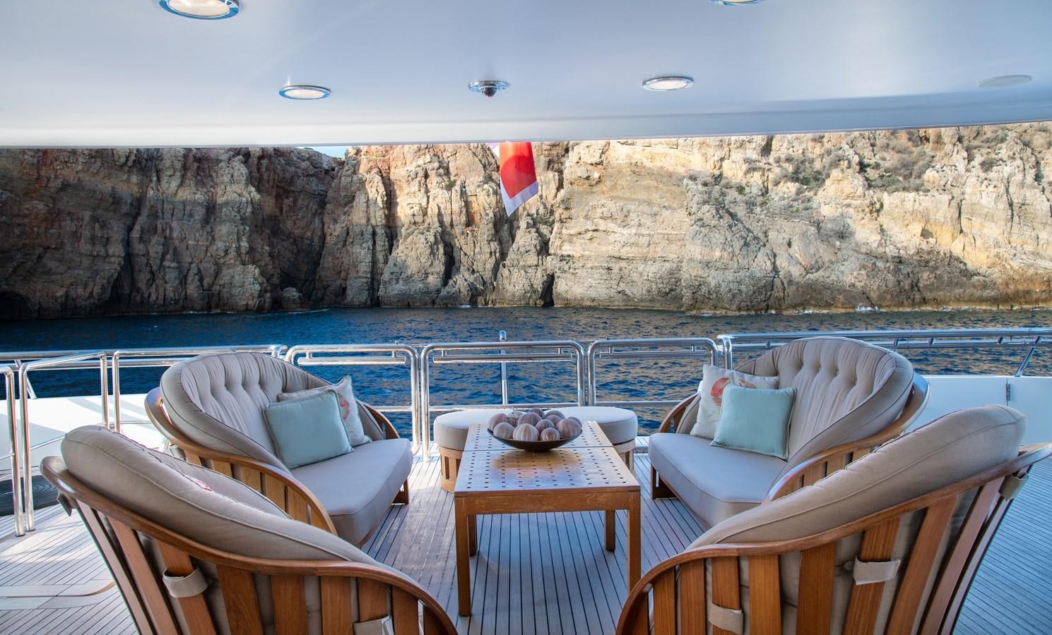 a table and chairs on a deck overlooking a body of water aboard IRAVATI Yacht for Sale
