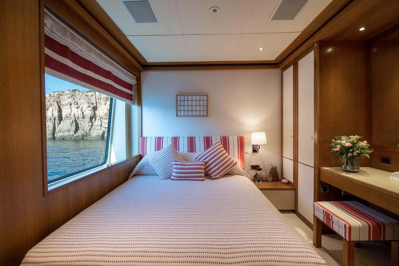 a bed with a white sheet and a pink and white striped pillow aboard IRAVATI Yacht for Sale