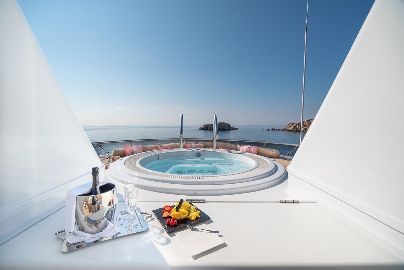 a white tent with a water fountain and a bottle of fruit on a table with a blue sky aboard IRAVATI Yacht for Sale