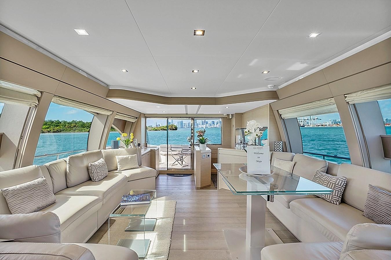 a living room with a large glass table and a view of the ocean aboard Mojo Yacht for Sale