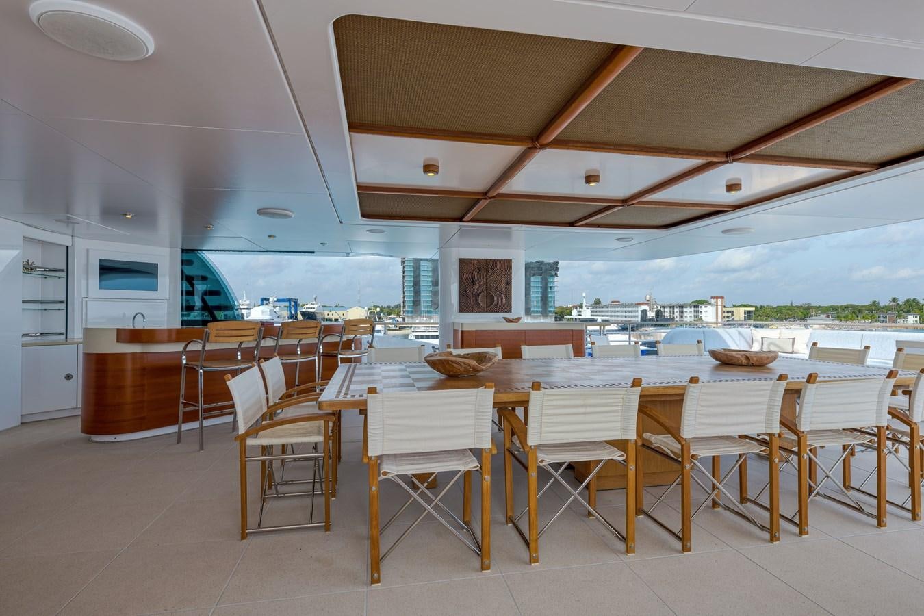 a large white table with chairs and a large patio with a view of the water and the ocean aboard KOGO Yacht for Sale