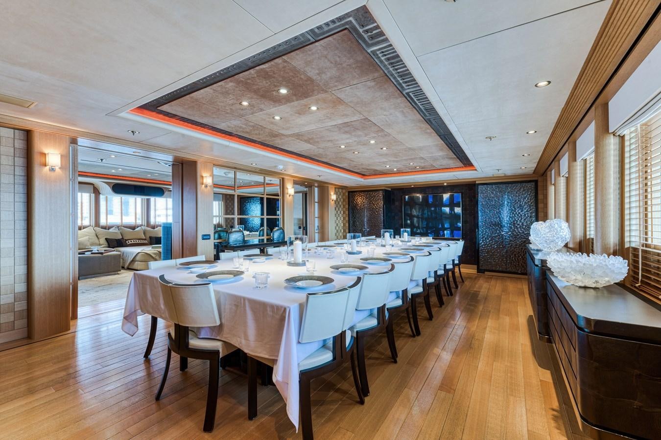 a long table with white cloths and chairs in a room with wood floors and a wood floor aboard KOGO Yacht for Sale