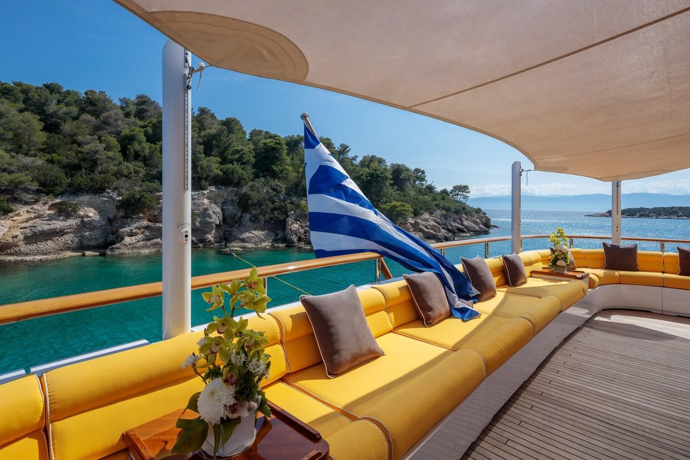 a yellow lounge chair on a balcony overlooking a body of water aboard VERA Yacht for Sale