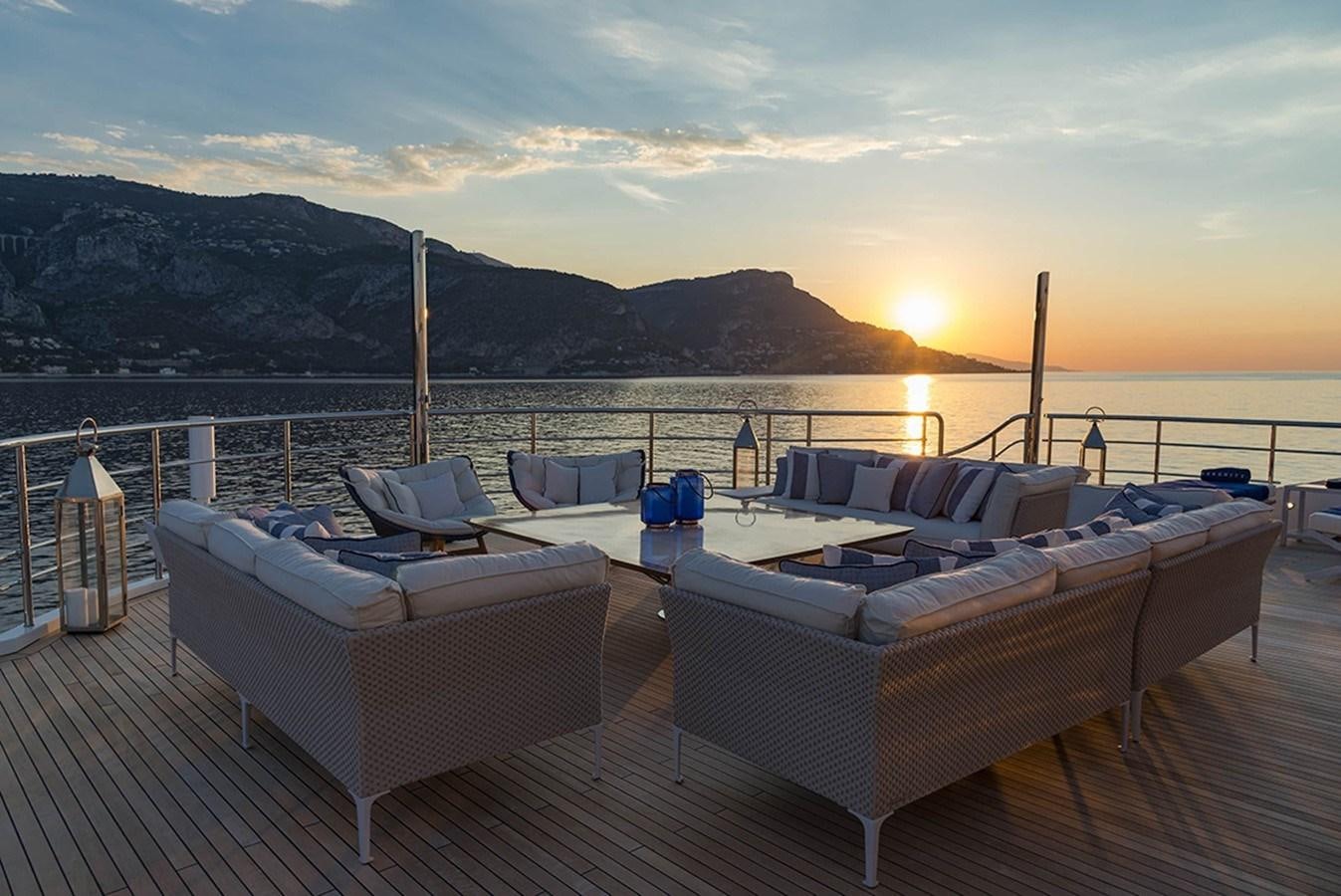 a deck with a view of the sunset and mountains in the background aboard MARQUISE Yacht for Charter