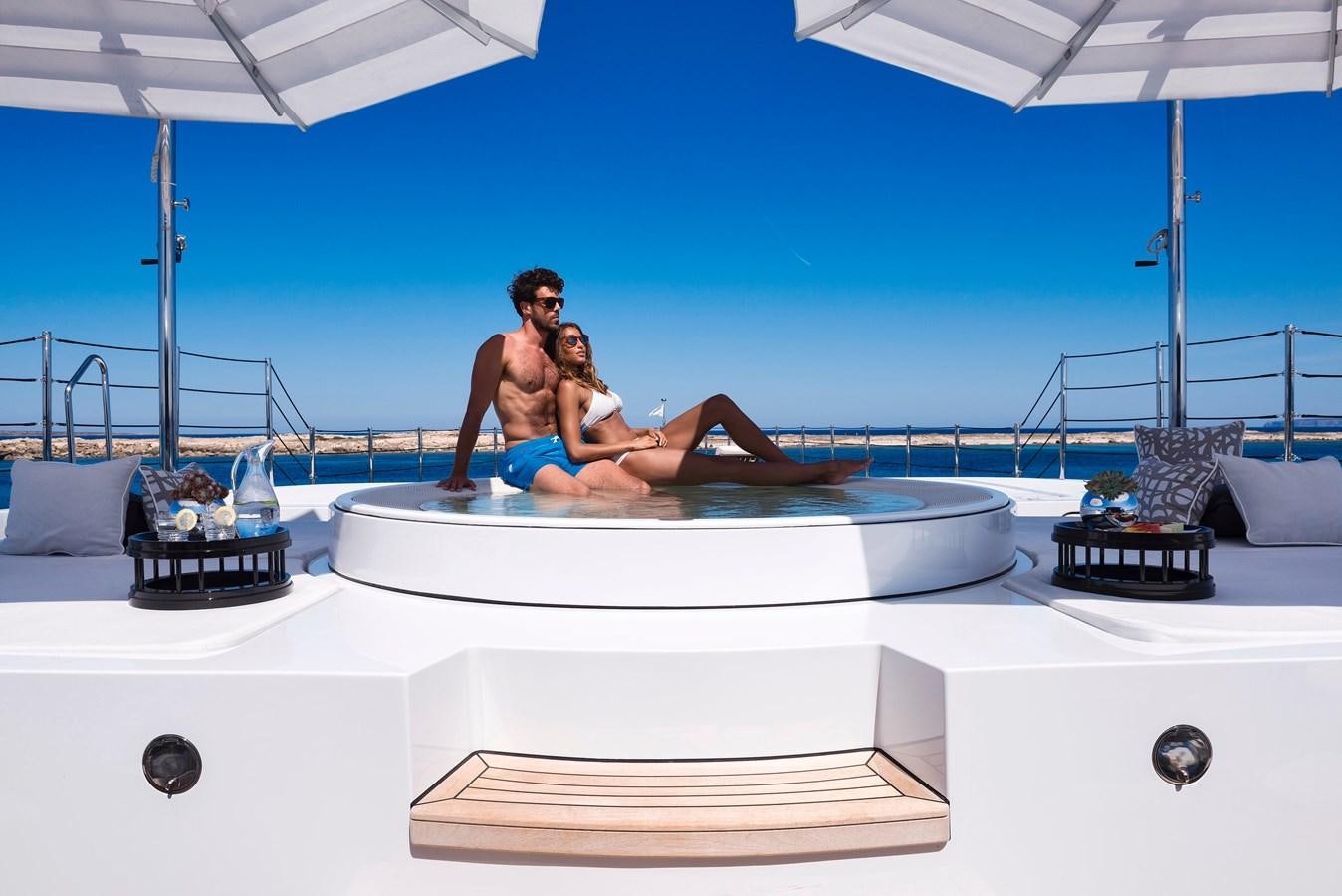 a couple of women sitting on a white lounge chair on a white table aboard SOUNDWAVE Yacht for Sale