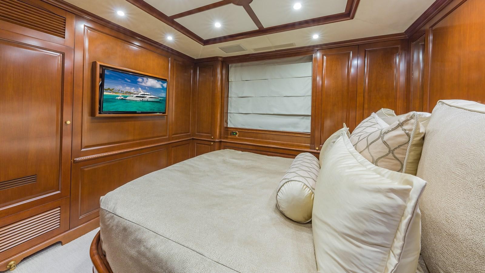 a bed with a white pillow and a television on the wall aboard NAMASTE Yacht for Sale