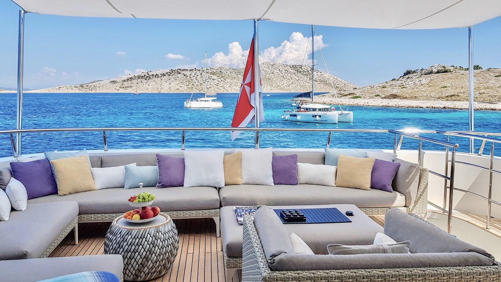 a couch and a table on a beach with a boat in the background aboard BALTIC SEA Yacht for Sale