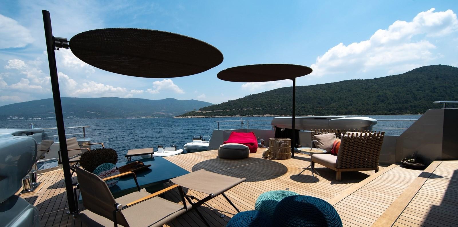 a deck with a chair and umbrella aboard CALADAN Yacht for Sale