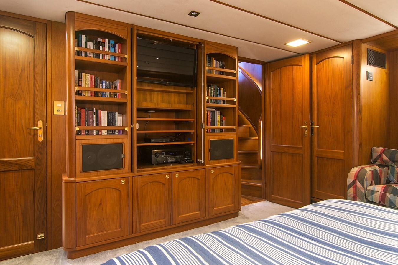 a bedroom with a bed and a bookcase aboard MOONSHADOW NOA Yacht for Sale