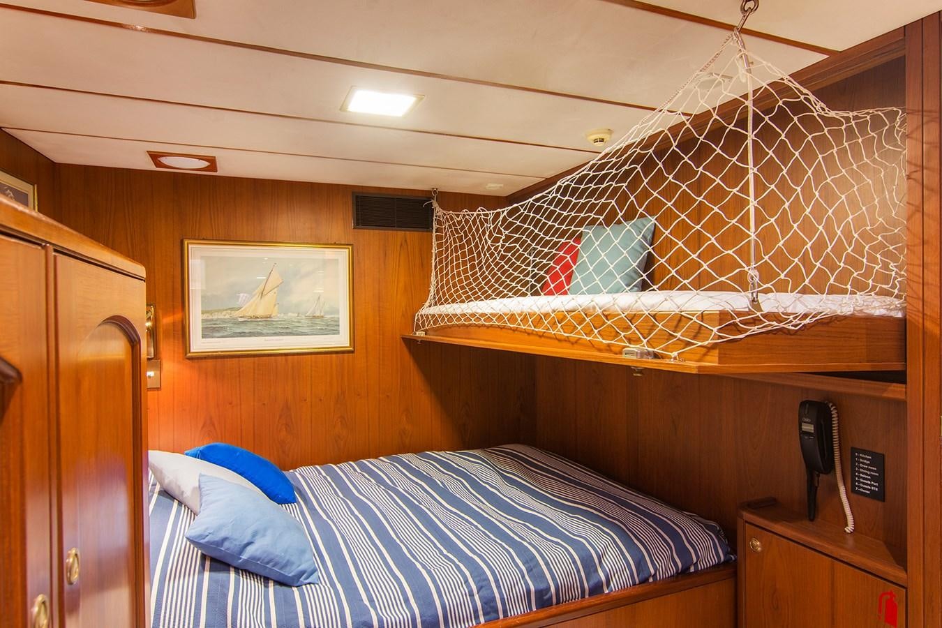 a bed with a blue and white striped pillow and a wooden headboard aboard MOONSHADOW NOA Yacht for Sale