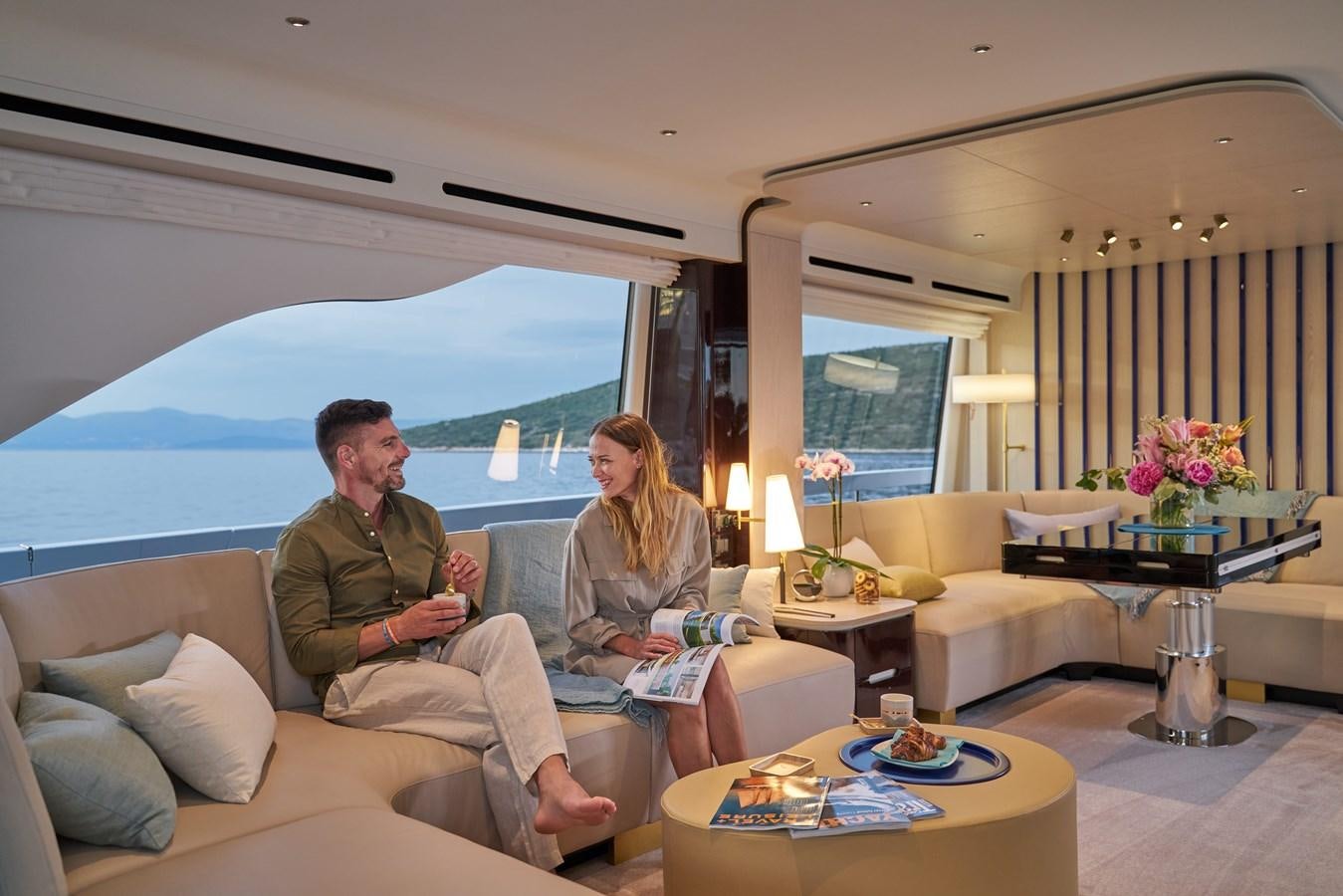 a man and a woman sitting on a couch in front of a large blue tent aboard VIVA Yacht for Sale