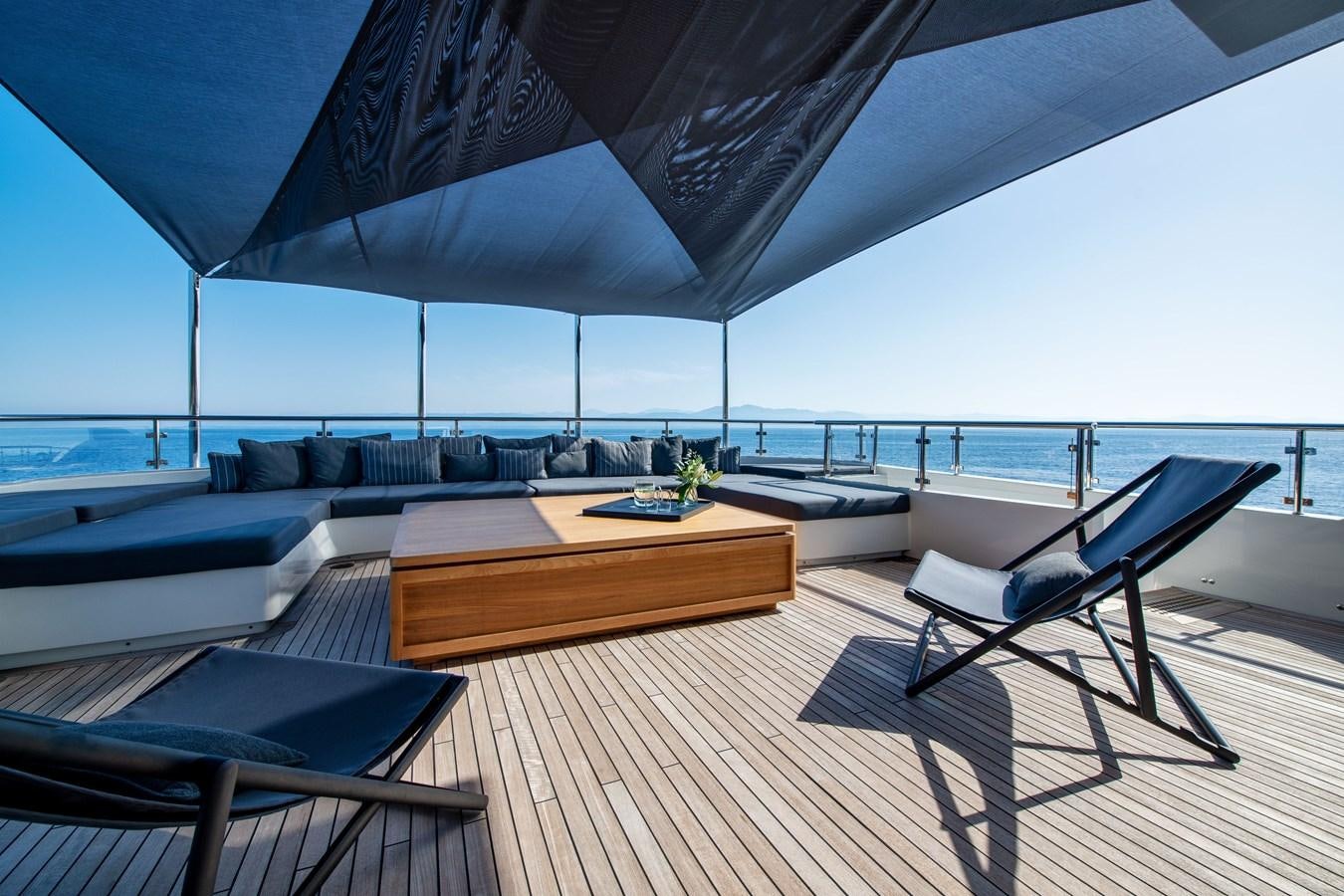 a room with a large bed and a table with chairs aboard ZIA Yacht for Sale