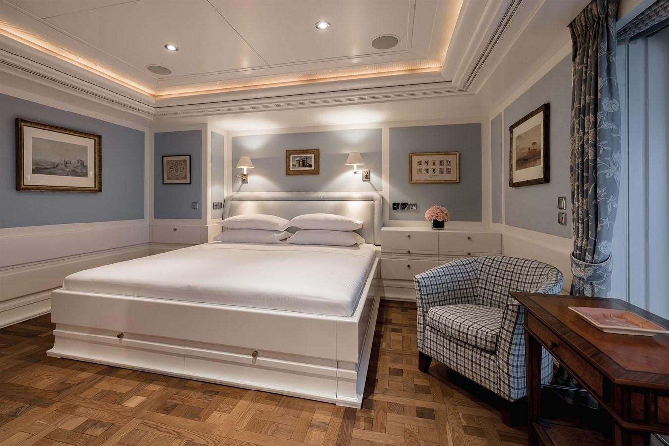 a bedroom with a bed and a chair aboard CARINTHIA VII Yacht for Sale