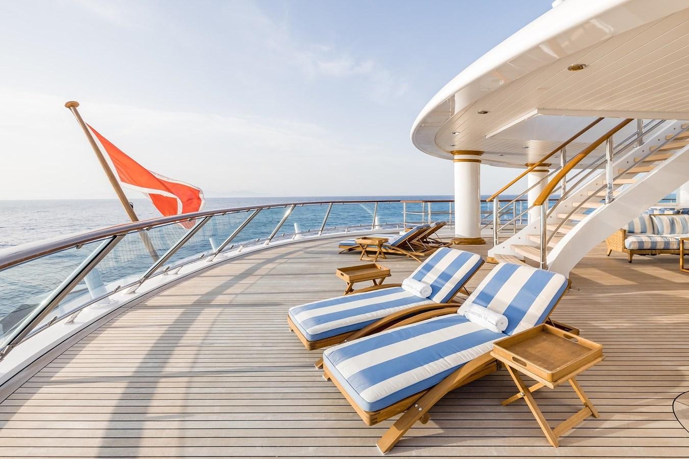 a deck with chairs and a large sailboat on it aboard CARINTHIA VII Yacht for Sale