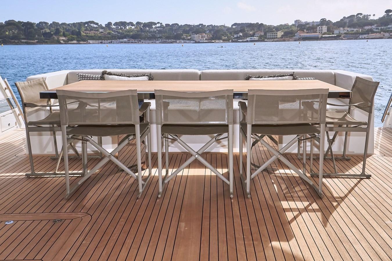a group of white chairs on a deck overlooking a body of water aboard SL96A Yacht for Sale