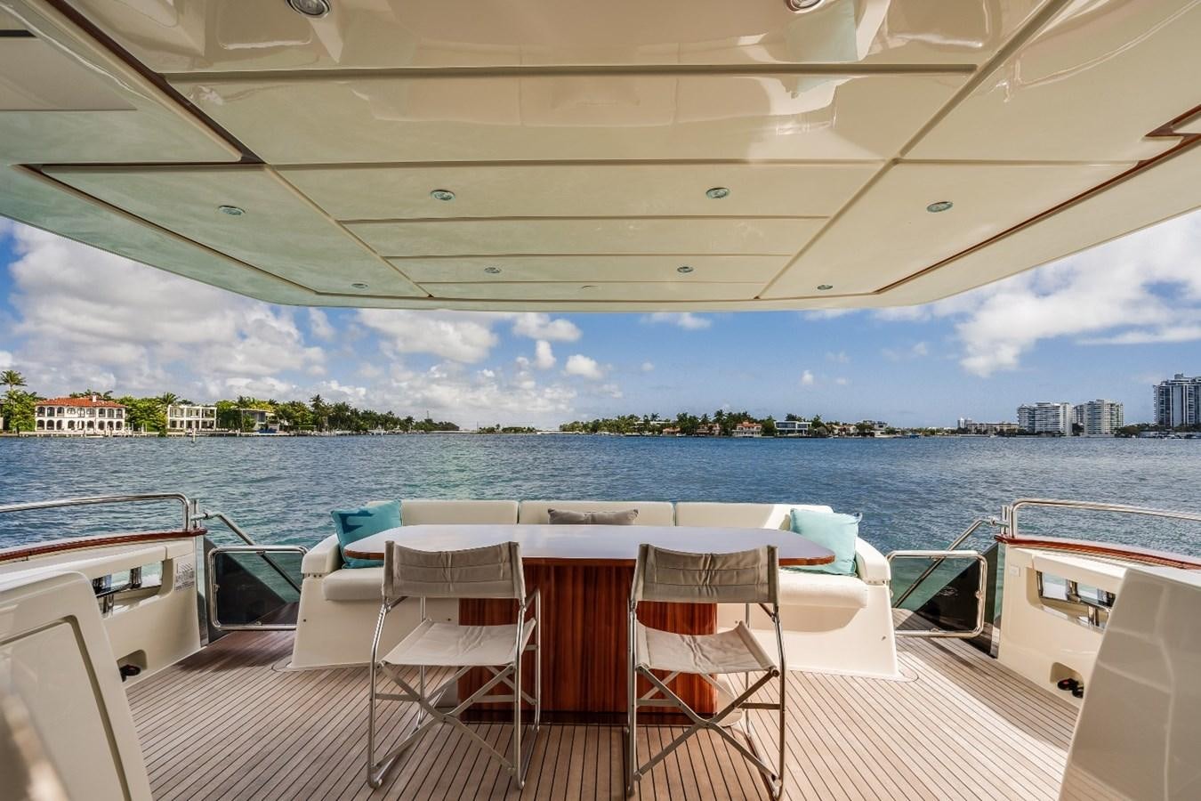 a deck with chairs and tables on it by a body of water aboard NAMEDROPPER Yacht for Sale