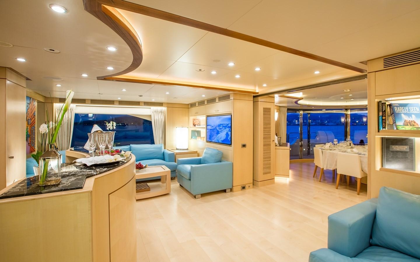 a room with a table chairs and a television aboard BLUE VISION Yacht for Charter