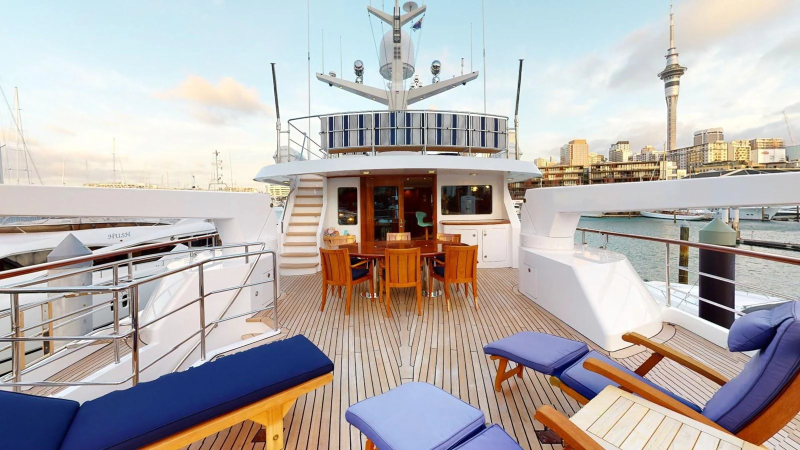a deck with a view of a city and a large ship aboard ADYTUM Yacht for Sale
