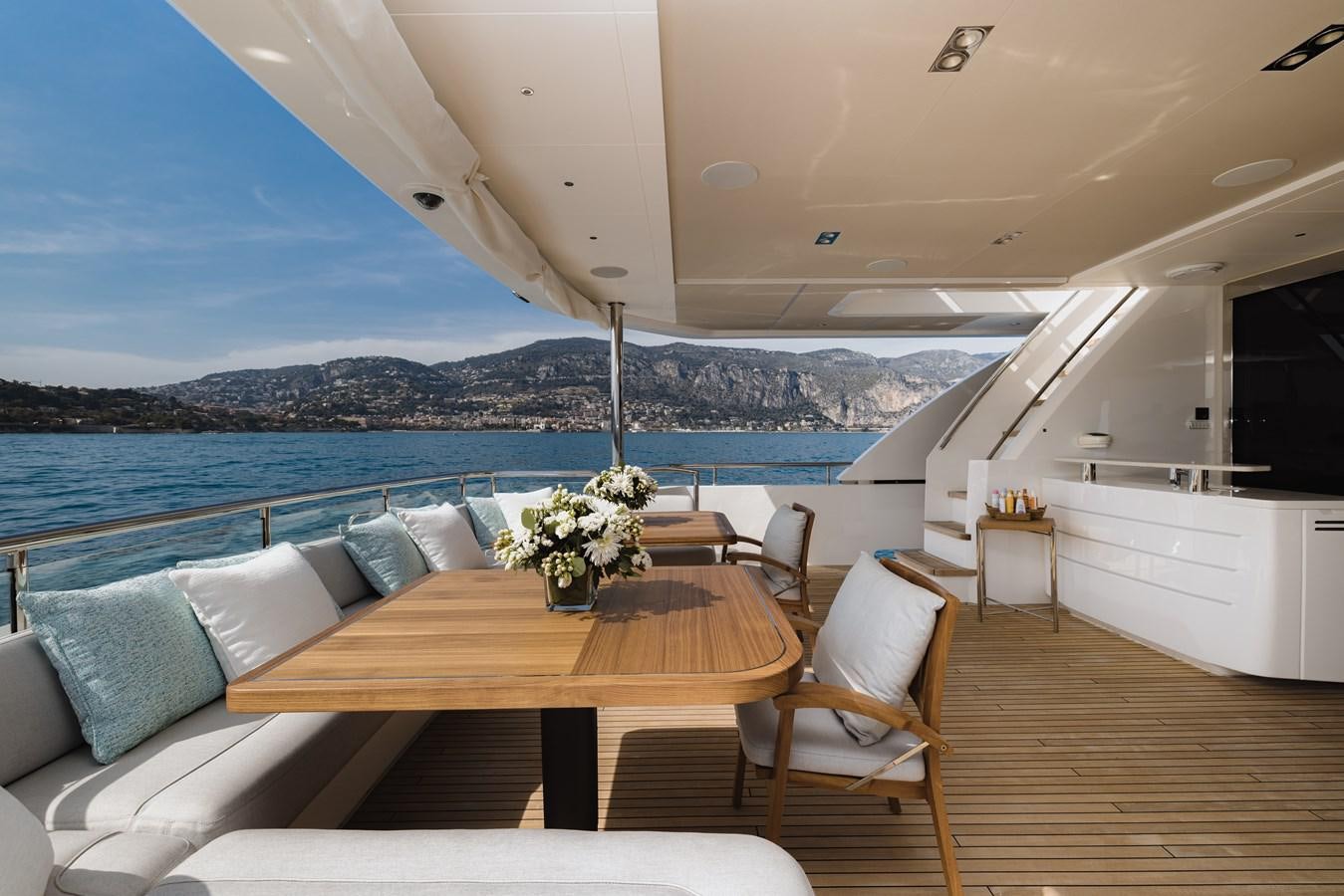 a table and chairs on a deck overlooking a large body of water aboard RIVIERA LIVING Yacht for Sale