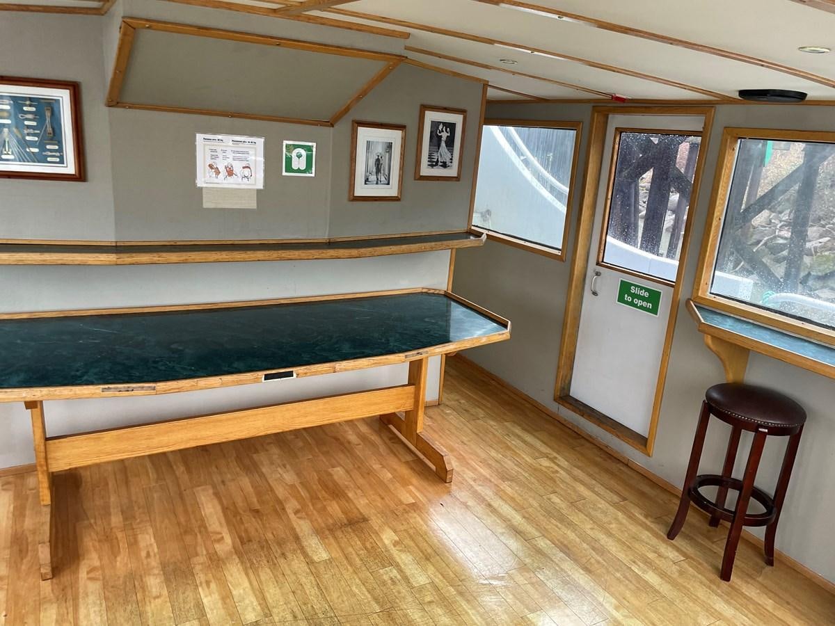 a room with a bench and stools aboard MAGIC MOMENT Yacht for Sale