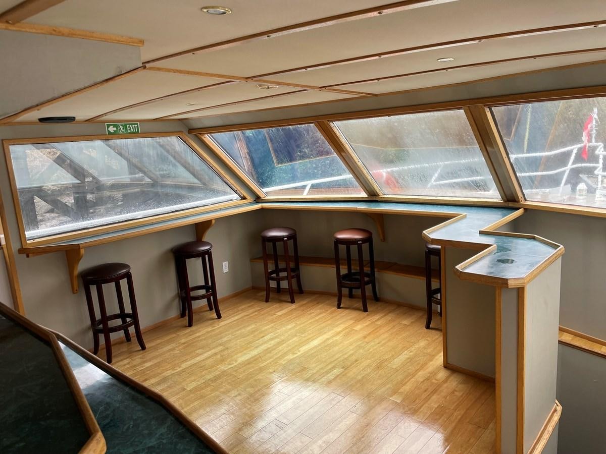 a room with a table and stools aboard MAGIC MOMENT Yacht for Sale
